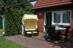 Terrasse mit Standkorb, Gartentisch und Stühlen